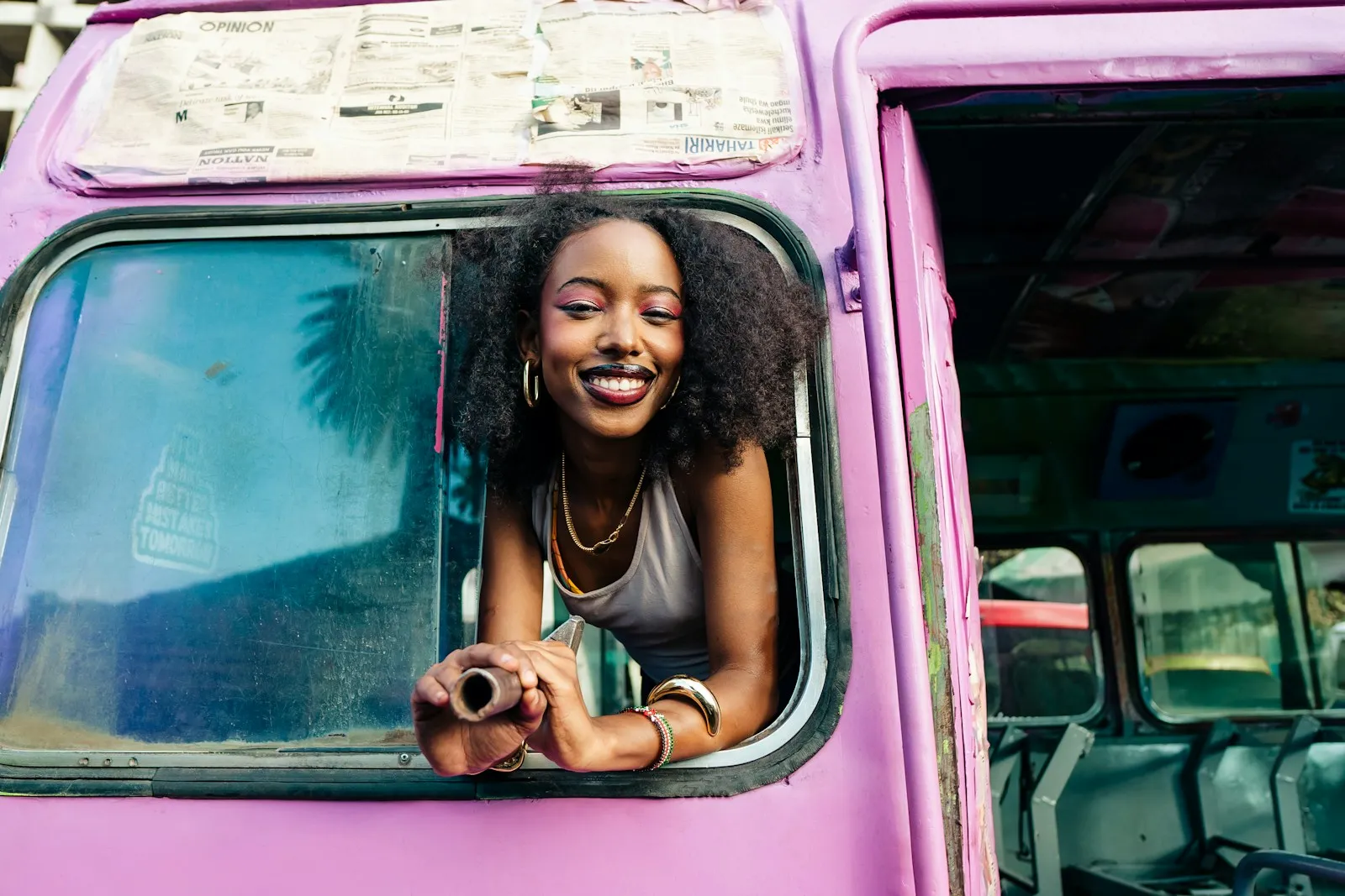 A smiling woman leaning out of a bus window