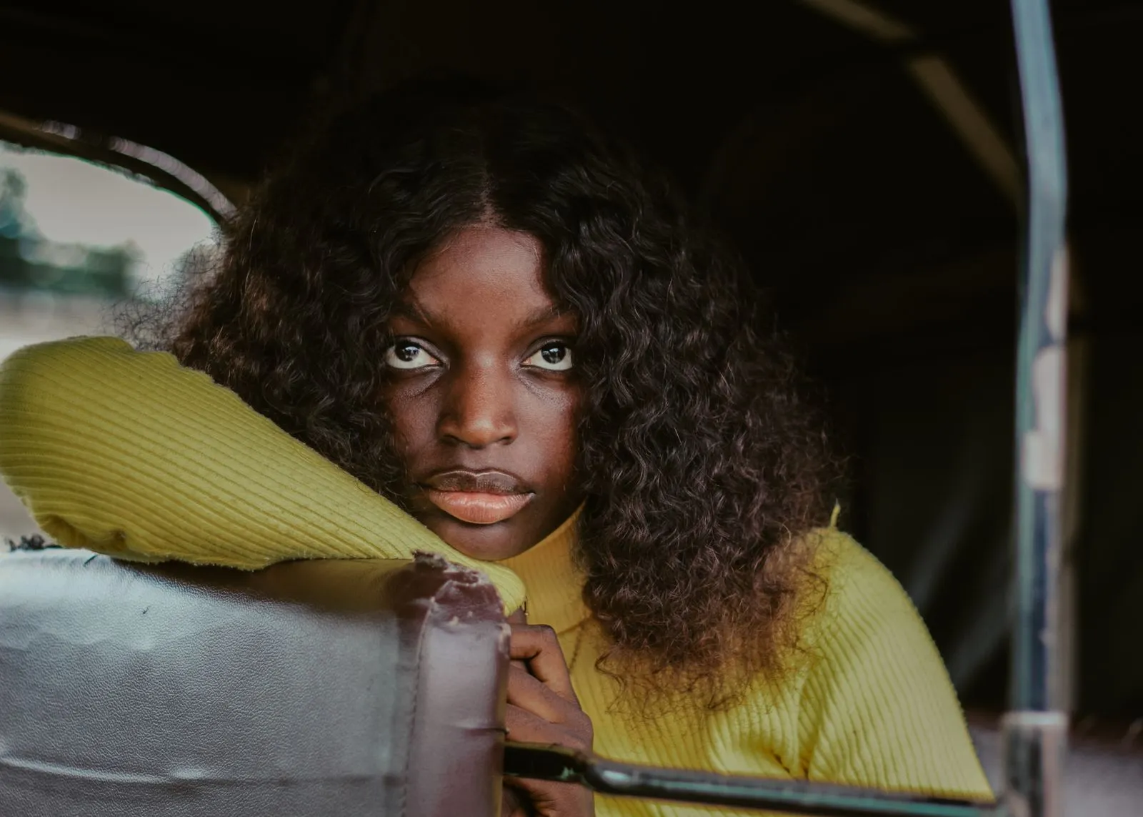 A thoughtful young woman looking out from a vehicle