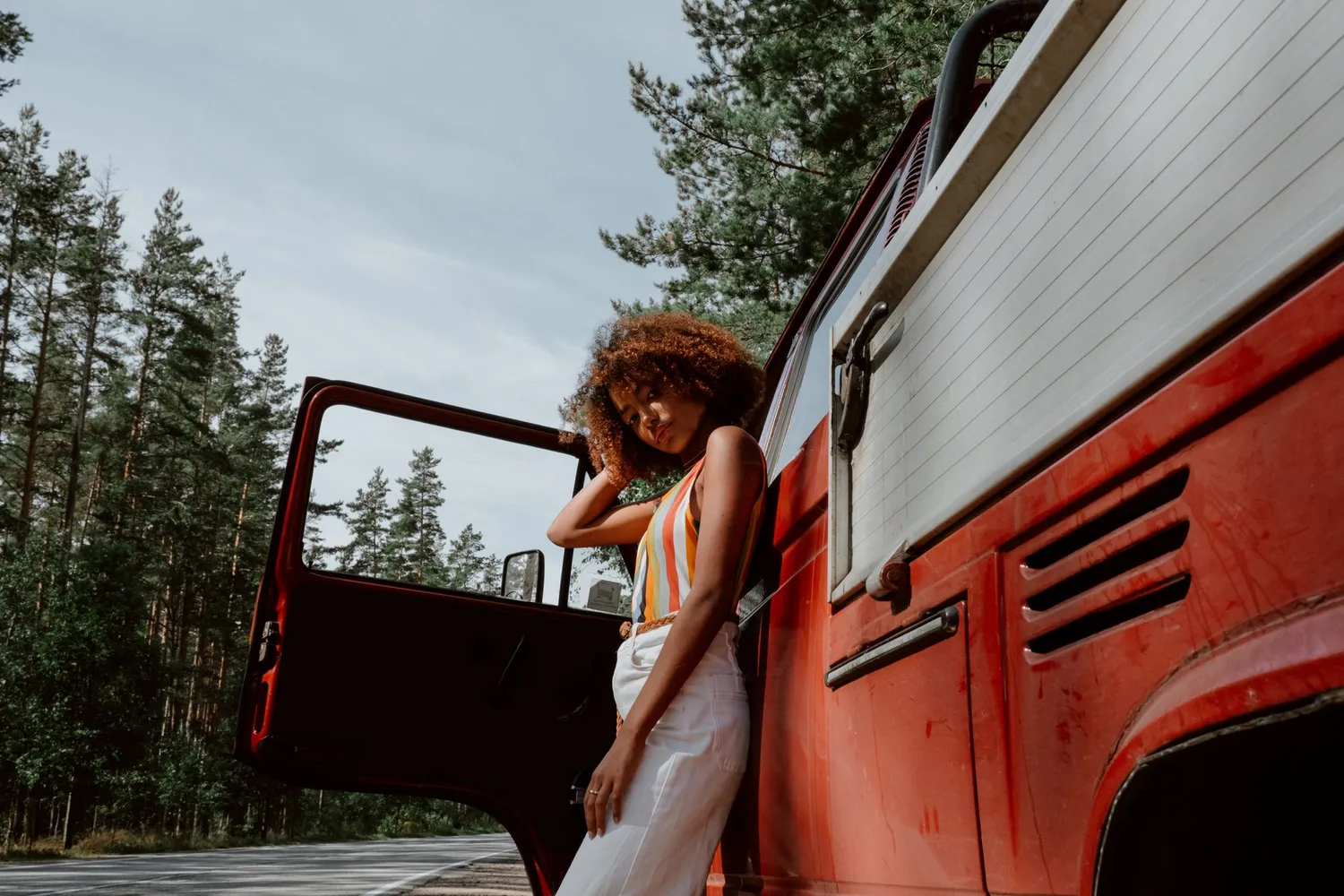 A traveler beside a vintage van on a forest road